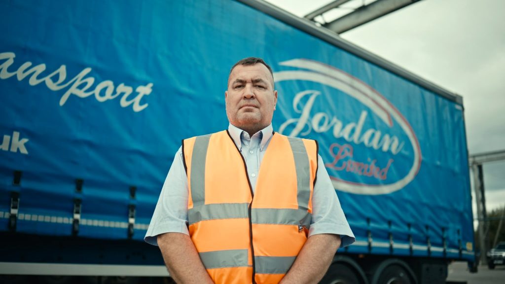 Jordan TM team member Colin Wilson in high-visibility clothing in front of a branded blue trailer