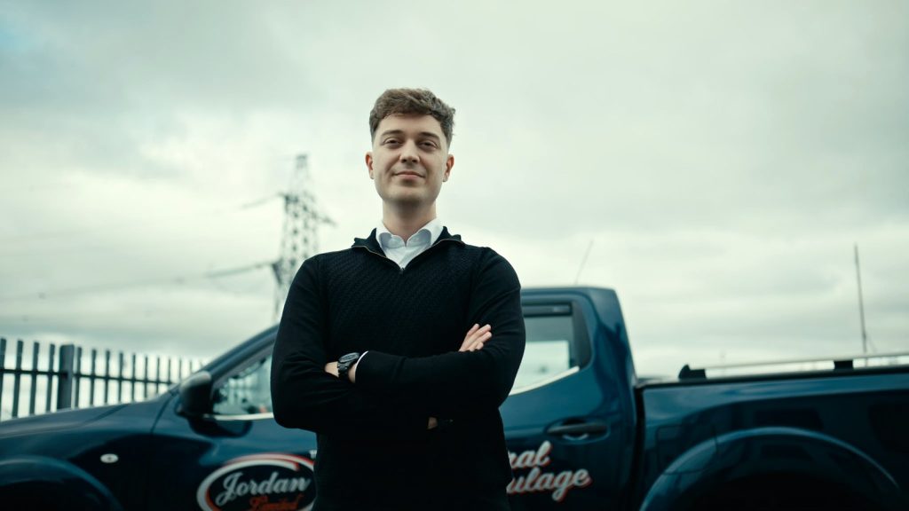 Jordan TM team member standing beside a branded company vehicle.